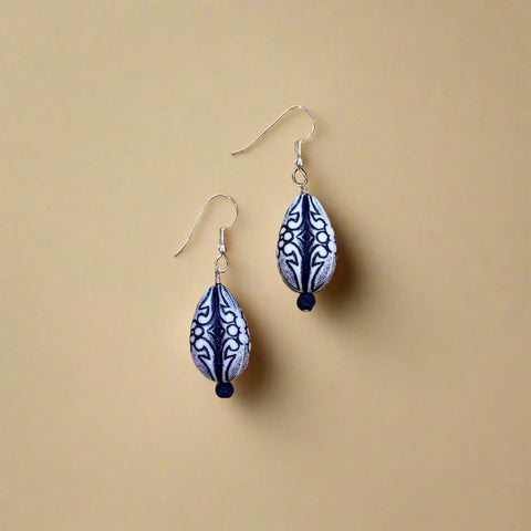 Pair of blue and white patterned earrings on a wooden surface