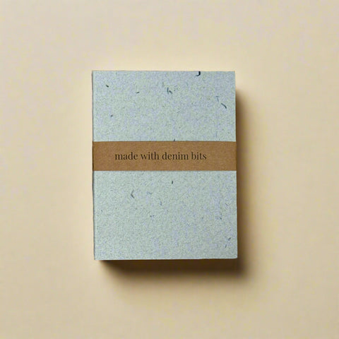 Notebook with denim bits on a cardboard background, featuring the VistaPrint logo.