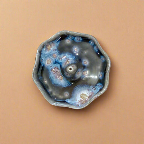 Ceramic incense holder with unique blue and gray glaze pattern on a wooden surface