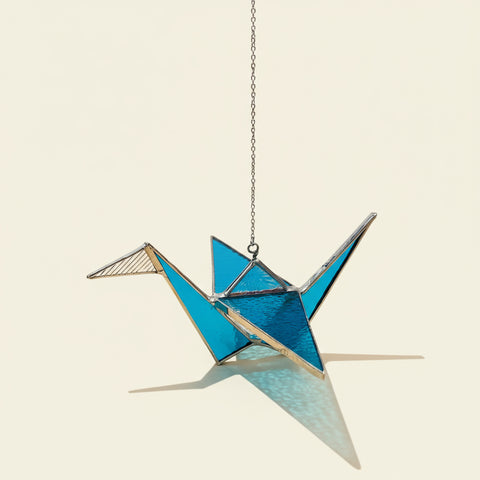 Decorative crane-shaped suncatcher on a chain.