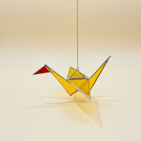 Yellow stained glass ornament on a wooden surface with a blurred background.