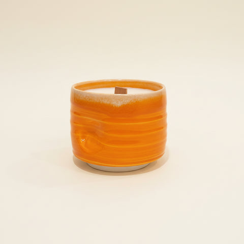 Orange candle in a textured holder.