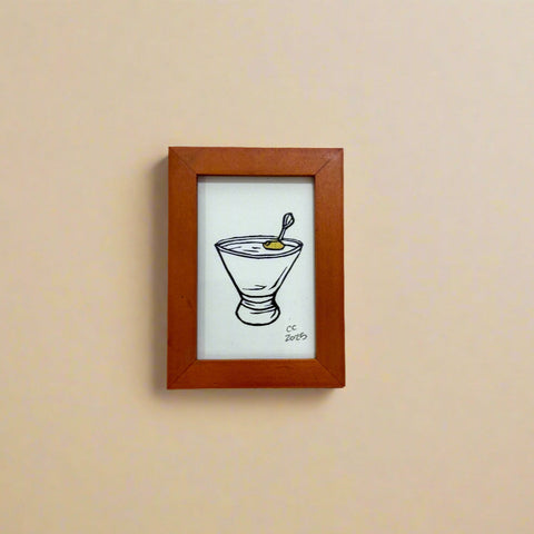 Small framed drawing of a cocktail on a wooden surface