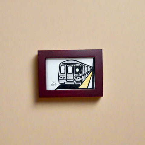 Framed artwork of a train on a wooden surface