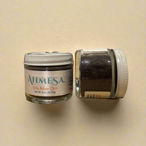 Two jars of Ahmesa salt on a wooden surface