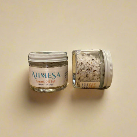 Two jars of salt on a wooden surface.