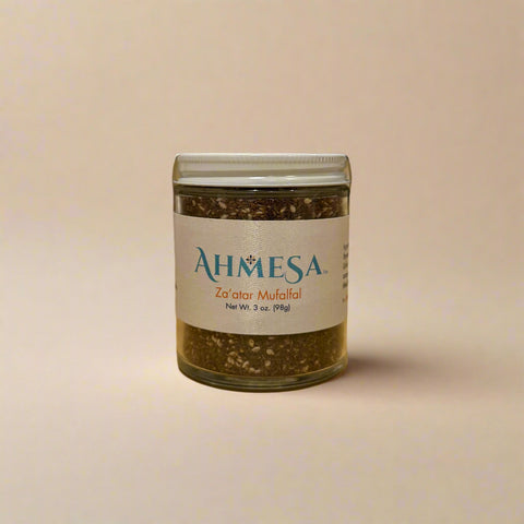 Jar of Ahmesa za'atar mufalfal seasoning on a wooden surface.