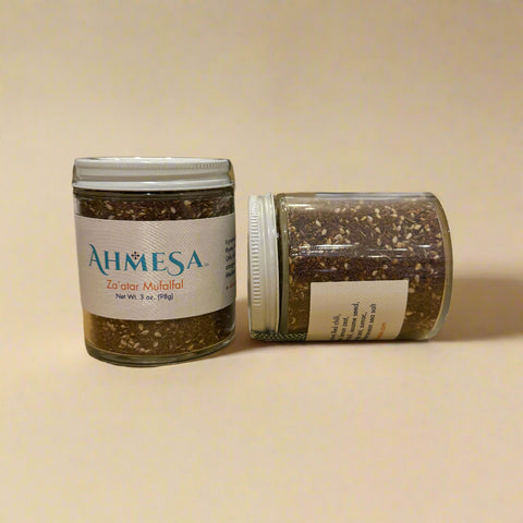 Two jars of Ahmesa Za'atar Mulalal on a wooden surface.