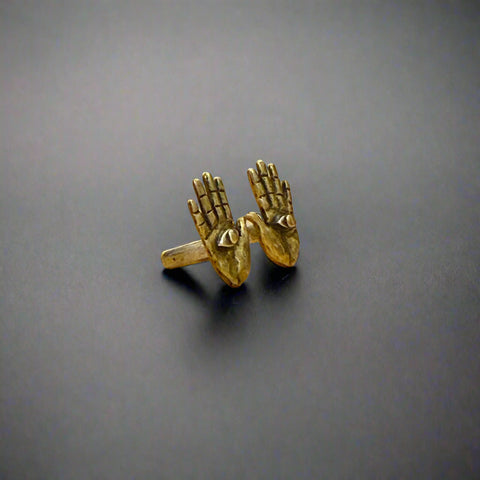 Bronze hand-shaped ring on a wooden surface with a blurred background