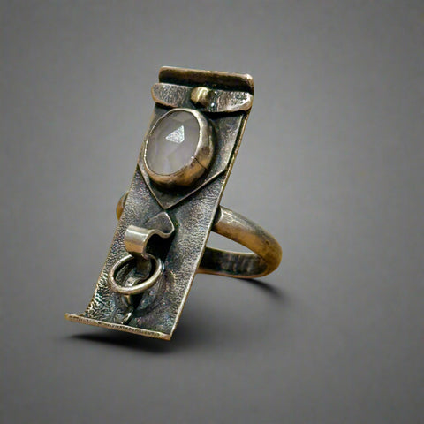 Silver ring with a central stone on a wooden surface
