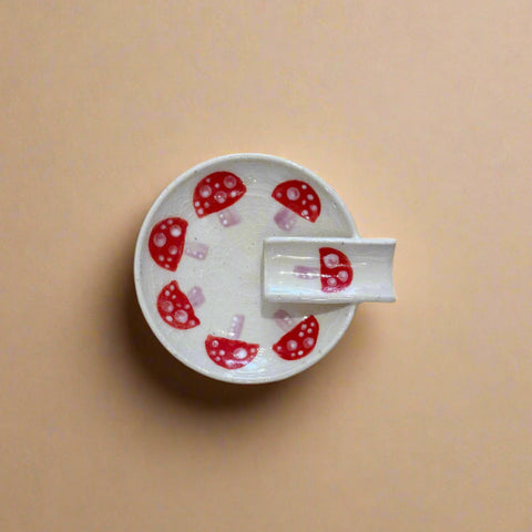 White ceramic dish with red mushroom design on a wooden surface