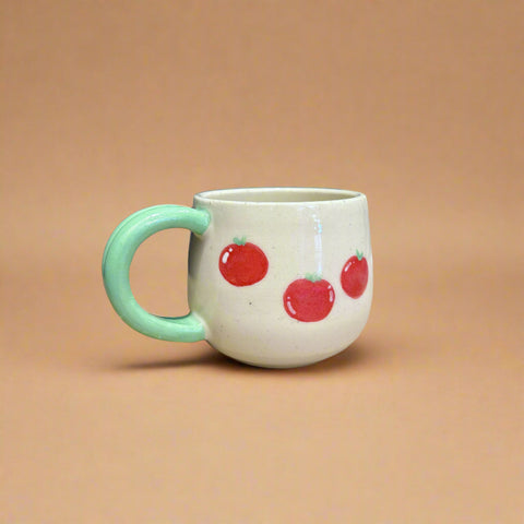 Mug with red apple design on a cardboard surface with a blue curtain background