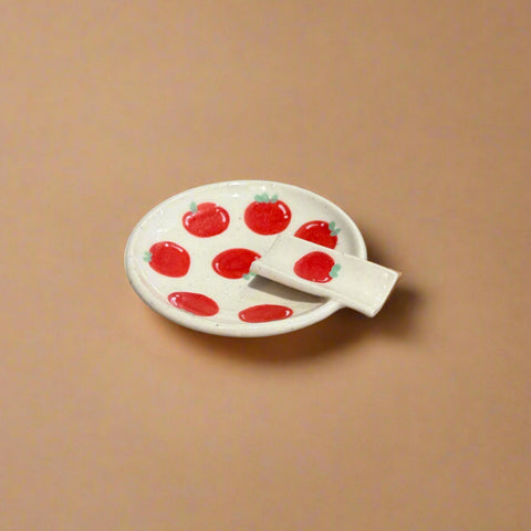 Small white plate with red apple design on a cardboard surface