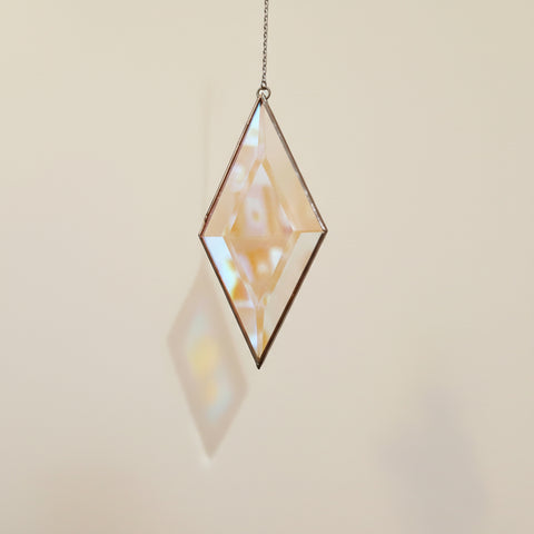 Geometric glass hanging ornament on a plain background