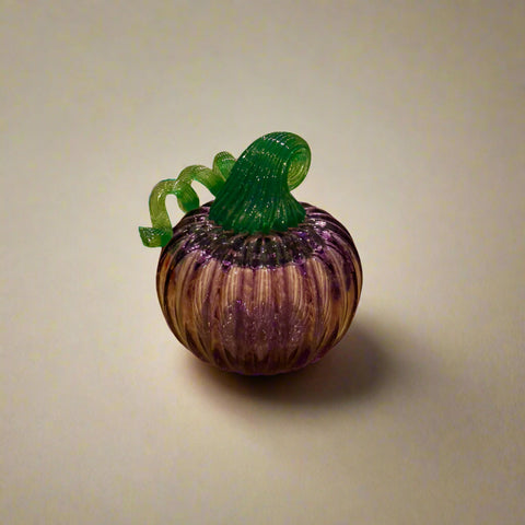 Glass pumpkin figurine on a wooden surface with a store interior in the background