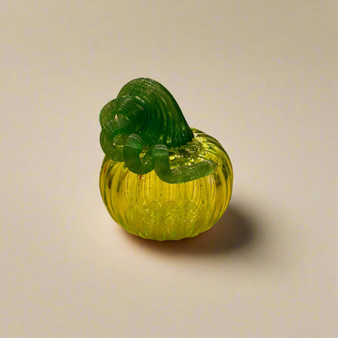 Green glass pumpkin on a wooden table with store interior in the background