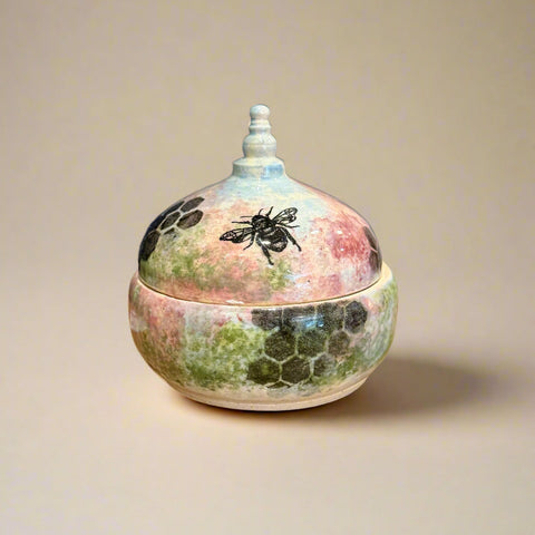 Decorative ceramic pot with lid featuring a bee design.