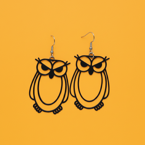 A pair of 3D printed owl-shaped earrings displayed on a yellow background