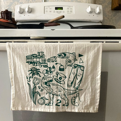 White towel with black illustrations hanging on a stove handle