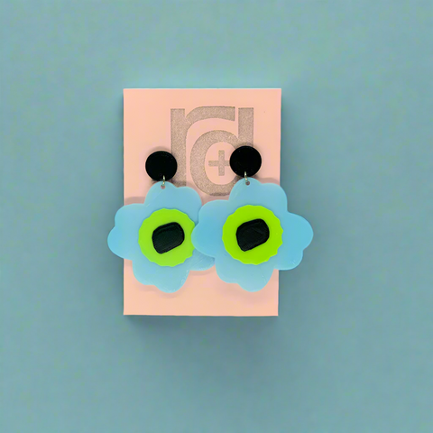 Flower-shaped earrings on a pink card with a visible brand logo.
