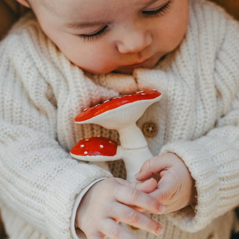 Baby holding a red and white mushroom-shaped toy