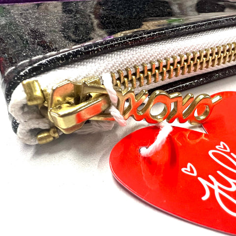 Close-up of a pouch with a gold zipper and a red tag with white text.