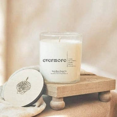 Candle labeled 'sweet comfort' on a wooden stand with soft lighting