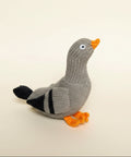 Knitted pigeon toy with orange beak and feet on a blue background