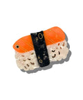Sushi-shaped compact mirror with orange rice, black seaweed, and white fish on a white background
