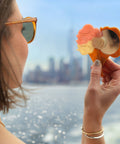 Person holding a compact mirror with floral design by a waterfront
