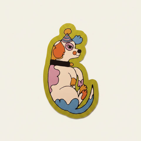 Colorful sticker of a dog with a party hat on a pink fabric background