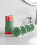 Set of green tins with a colorful cylindrical container on a white background