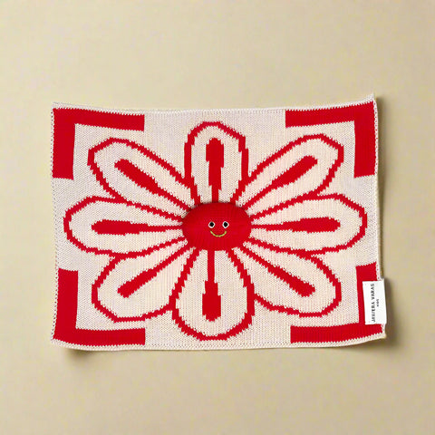 Red and white knitted blanket with a smiley face design on a white background