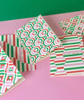 Set of Christmas-themed greeting cards with geometric patterns on a pink surface.