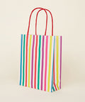 A multicolored striped paper gift bag with red handles.
