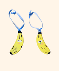 Two cartoon-style banana-shaped ornaments with blue ribbon on a beige background
