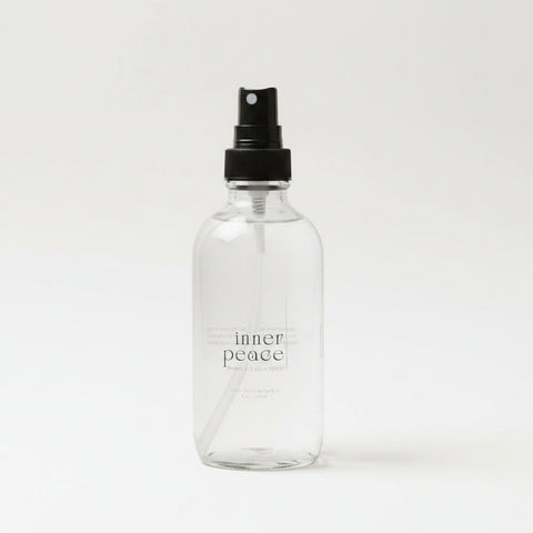 Clear spray bottle labeled 'inner peace' on a light surface with soft lighting.