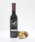 Bottle of Saratoga Olive Oil Co. Fig Balsamic Vinegar with figs on a white background