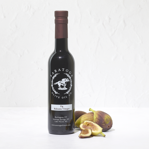 Bottle of Saratoga Olive Oil Co. Fig Balsamic Vinegar with figs on a white background