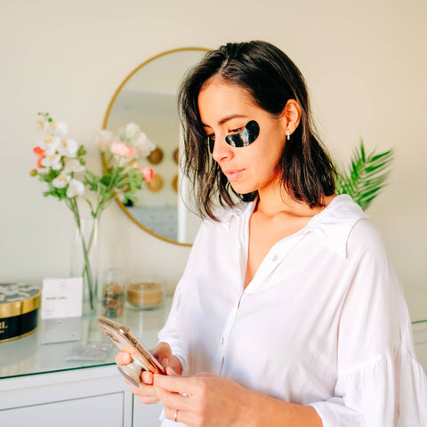 Woman in a white shirt using a phone in a room with decor elements.