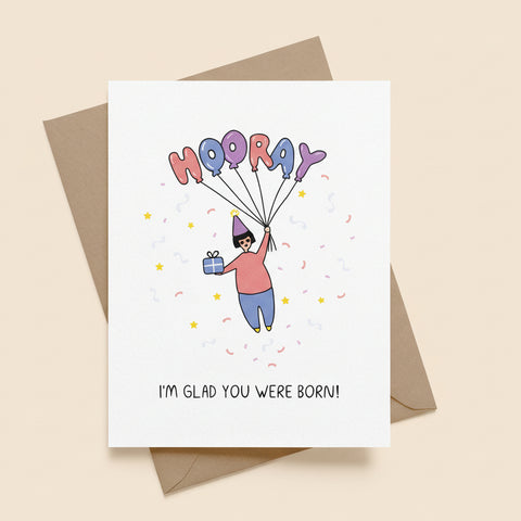 Greeting card with cartoon illustration and 'Hooray! I'm glad you were born!' text on a white background