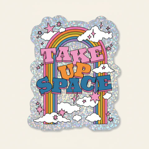 Sticker with rainbow, stars, and clouds with 'Take Up Space' text on a light gray background