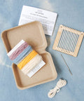 Knitting kit with yarn, needles, and instructions on a blue background