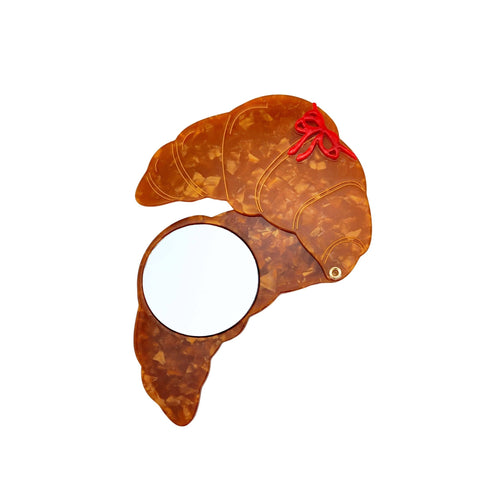 Decorative item shaped like a croissant with a red bow on a white background