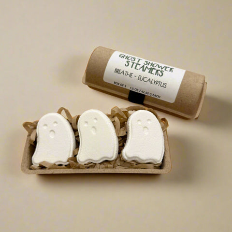 Ghost-shaped shower steamers with a cardboard tube labeled 'Ghost Shower Steamers' on a wooden surface.