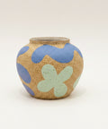 A small round ceramic vase with a speckled tan glaze, decorated with wavy blue and mint green shapes.
