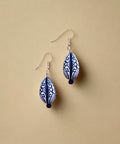 Pair of blue and white patterned earrings on a wooden surface