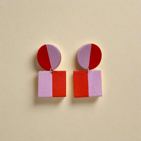 Pair of earrings with geometric design on a wooden surface
