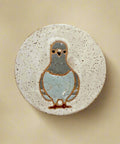 Ceramic coaster with a pigeon design on a wooden surface