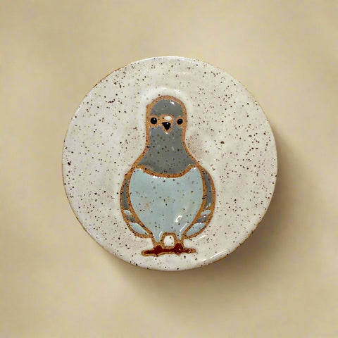 Ceramic coaster with a pigeon design on a wooden surface
